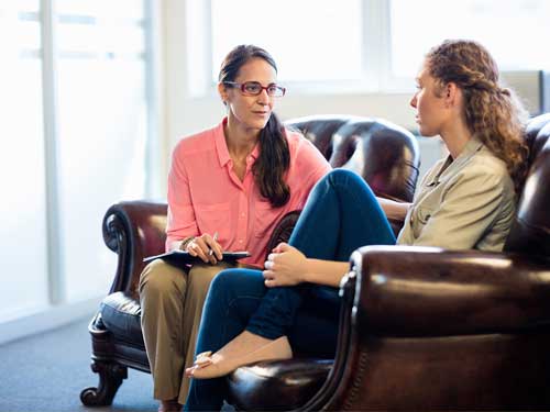 θεραπεύτρια συζητάει με θεραπευόμενη στο γραφείο της